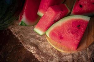 melancia e pedaços de melancia em um fundo de madeira foto