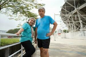 feliz e sorrir casais idosos ásia em pé em escadas para descansar depois de dar certo, corrida em manhã, Senior exercício ao ar livre para Boa saudável. conceito do cuidados de saúde e ativo estilo de vida para saudável foto