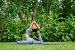retrato do uma jovem mulher fazendo ioga dentro a jardim para uma dar certo. conceito do estilo de vida ginástica e saudável. ásia mulheres estão praticando ioga dentro a parque. foto