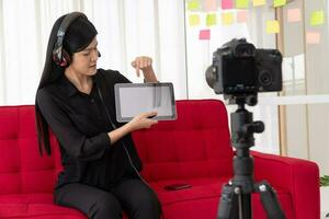 vlog mulher asiática blogueira influenciadora sentada no sofá em casa e gravando blog de vídeo para ensinar e treinar seus alunos ou assinantes. conceito do criador de conteúdo online para um novo estilo de vida foto