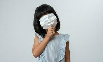 retrato do engraçado ásia menina criança com protetora face mascarar. conceito do criança indo costas para escola e Novo normal estilo de vida foto