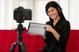vlog mulher asiática blogueira influenciadora sentada no sofá em casa e gravando blog de vídeo para ensinar e treinar seus alunos ou assinantes. conceito do criador de conteúdo online para um novo estilo de vida foto