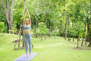 retrato do uma jovem mulher fazendo ioga dentro a jardim para uma dar certo. conceito do estilo de vida ginástica e saudável. ásia mulheres estão praticando ioga dentro a parque. foto