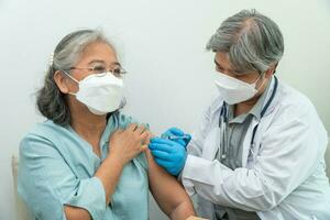 os médicos usam máscaras médicas e vacinam pacientes idosas para a prevenção de coronavírus e gripe. conceito de imunização de inoculação foto