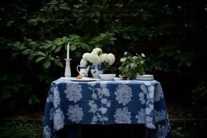 uma encantador ao ar livre chá festa configuração com azul e branco toalha de mesa foto