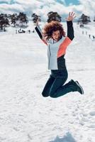 mulheres felizes pulando no ar e se divertindo na neve no dia ensolarado de inverno.