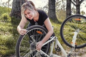 mulher conserta sua bicicleta
