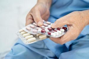 Paciente asiático, mulher idosa ou idosa segurando pílulas de antibióticos em embalagem blister para tratamento de infecção de paciente no hospital foto