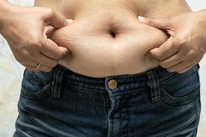 mulher asiática com sobrepeso mostra barriga gorda no escritório. foto