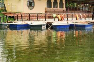 remo barcos ficar de pé às a cais em a lago dentro a cidade parque. linha de madeira navios ancorado em a cais. ao ar livre atividade. família fim de semana. de várias barcos com remos. saudável estilo de vida. urbano lazer período de férias foto