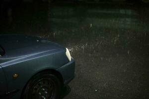 carro dentro chuva. luminária do carro brilha através pingos de chuva. viagem às noite dentro tempestade. foto