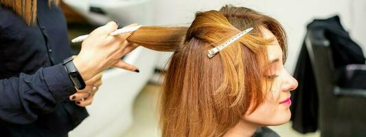 a fêmea cliente recebendo uma corte de cabelo às a beleza salão, jovem mulher desfrutando obtendo uma Novo Penteado. foto