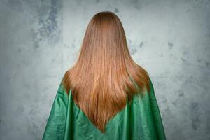 traseiro Visão do uma mulher com grandes Castanho cabelo contra uma cinzento fundo. foto