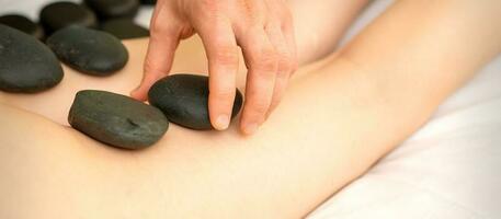 uma mulher obtendo spa quente pedra terapia pernas massagem procedimento dentro uma beleza salão. foto