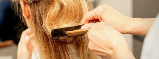 uma cabeleireiro é pentear fêmea estilo de cabelo dentro uma cabeleireiro beleza salão. foto