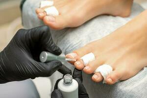 pedicure aplicando transparente verniz para a fêmea unhas dos pés dentro uma beleza salão. foto