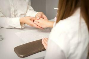 manicure mestre massageando fêmea mãos antes unha procedimento dentro uma unha salão. foto