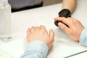 fechar-se do manicure mestre prepara mãos do uma jovem mulher para manicure procedimentos. foto