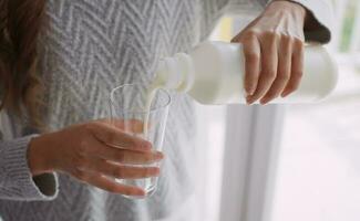 jovem mulher derramando leite para dentro vidro. foto