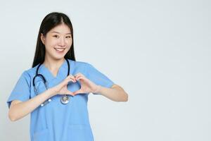 retrato do sorridente jovem mulher médico faz uma coração forma com dela mão isolar em branco fundo. foto
