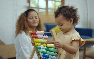 mãe e filha estão fazendo jogar uma brinquedo e tendo Diversão dentro vivo sala. foto