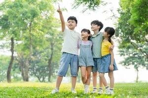 grupo do fofa ásia crianças tendo Diversão dentro a parque foto