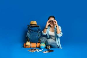 Mulher feliz jovem viajante asiático na camisa azul com mochila e equipamento para as férias dos viajantes com um mapa, sobre fundo de cor azul. mochila de viagem foto