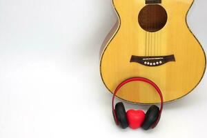 acústico guitarra, fones de ouvido e vermelho coração em uma branco fundo. amor, entretenimento e música conceito. foto