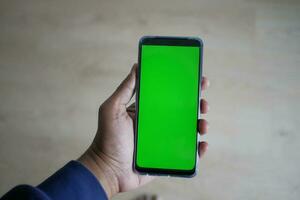 Feche a mão do jovem usando um telefone inteligente com tela verde foto