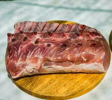 fresco todo cru carne de porco bife com costelas em uma de madeira cozinha borda. grande peça do porco carne fechar acima foto