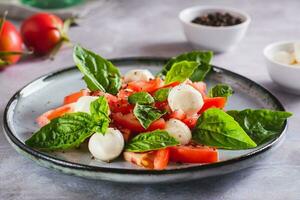 caprese salada com tomates, mussarela, manjericão e Oliva óleo em uma prato foto