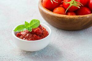 tomate colar e manjericão folhas dentro uma tigela e tomates em uma prato em uma luz fundo. vegetal e vegetariano Comida. vitaminas e desintoxicação dieta foto