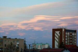 lenticular nuvens dentro a cidade acima a telhados do arranha-céus edifícios às pôr do sol. lindo céu foto