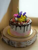 tiro do menina leitosa bolo fez do branco creme com chocolate glacê, decorado com flores e bagas foto