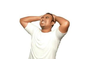 uma foto do uma ásia homem estressado dois mãos segurando estresse cabeça vestindo uma branco camiseta isolado de branco fundo. parece depressivo