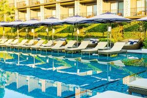 guarda-sol e cama ao redor da piscina externa em hotel resort para viagens de férias