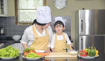 mulher asiática jovem mãe com filho menino cozinhando salada com vegetais segurando tomates e cenouras, pimentões no prato para família feliz cozinhar comida prazer estilo de vida cozinha em casa