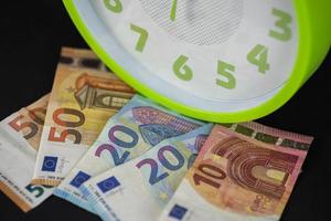 notas de euro sob um relógio foto
