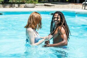 afro-americano homem e branco mulher jogando dentro uma piscina. foto