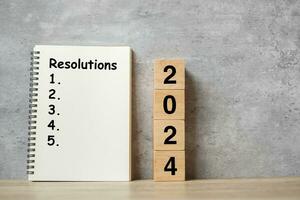 2024 feliz Novo ano com resolução caderno e de madeira número. contagem regressiva, metas, plano, açao e missão conceito foto