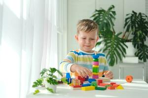 uma pequeno Garoto tocam com de madeira brinquedos e constrói uma torre. educacional lógica brinquedos para crianças. montessori jogos para criança desenvolvimento. crianças de madeira brinquedo. foto