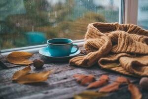 copo do café em uma de madeira outono fundo. chá e outono folhas perto a janela. café em a fundo do uma janela com chuva. foto