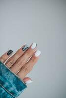 lindo fêmea mãos com uma manicure dentro uma jeans jaqueta. à moda unha Projeto. manicure com Preto e branco zebra listras em a unhas. foto