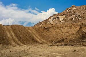 montes do areia e concreto detritos este ter fui escavado estão derramado juntos com retroescavadeira rodas. foto