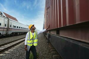 engenheiro inspeciona recipiente trem do transporte companhia distribuição e transporte do bens de trilho uma recipiente trem passagem através a industrial área foto