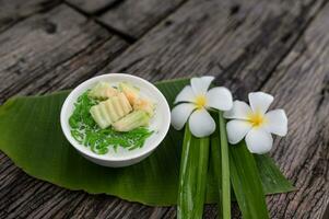 lod chong perfumado Pandan arroz gotejamento para dentro coco leite dentro uma de madeira tigela em uma verde banana folha fundo. ou lod chong misturado com tailandês melões ásia tailandês sobremesas foto