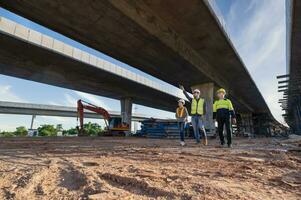 equipe do 3 ásia engenheiros inspecionando via Expressa construção. ásia arquiteto e maduro Supervisor encontro às via Expressa construção local foto