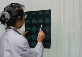 ásia mulher médico assistindo paciente raio X filme, mri e ct Varredura. saúde Cuidado conceito. foto