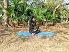 jovem indiana praticando ioga ao ar livre em um parque. linda garota pratica pose de ioga básica. calma e relaxamento, felicidade feminina. poses básicas de ioga ao ar livre foto