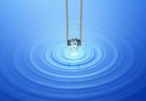 azul diamantes mantido dentro pinças em ondulado água com reflexão foto